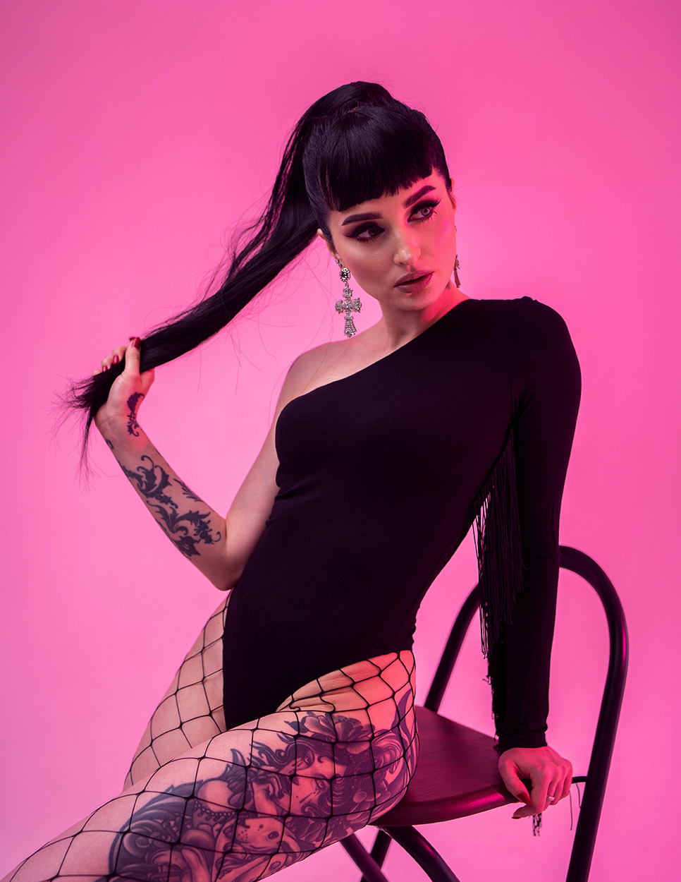 Hermosa mujer con tatuajes modelando sentada con cabello largo