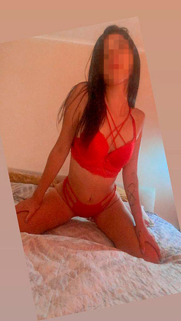 Hermosa escort con ropa interior roja en una cama