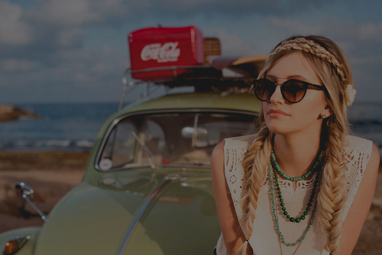 Mujer de viaje en una playa con su auto